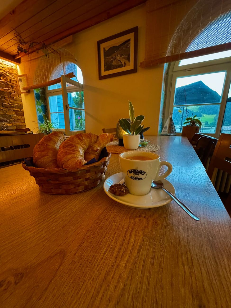 Gipfeli im Körbli und Kafi am Fenster mit Bergsicht im Bistro am See